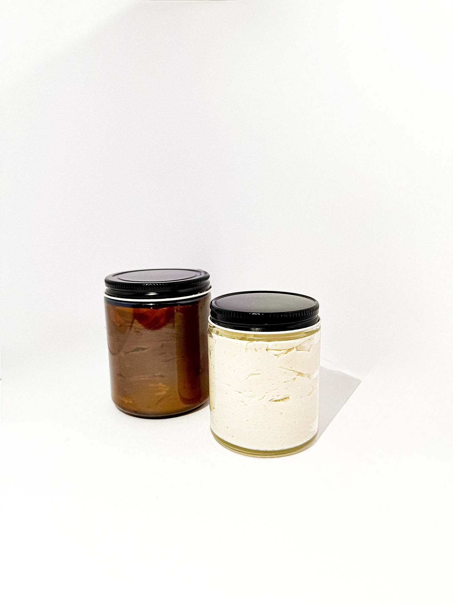 Large and medium glass jars filled with Aurora Vita Co.’s unscented whipped body butter. Luxurious, all-natural skincare in eco-friendly packaging.